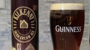Close up shot of the label on an empty can of Kilkenny nitro brew cream ale and a full glass marked with the Guinness nitro brew stout logo.